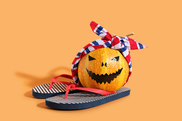 Halloween pumpkin on flip flops on orange background
