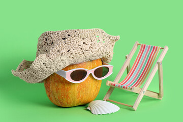 Halloween pumpkin in sunglasses with deckchair on green background