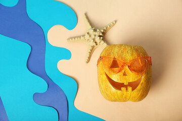 Halloween pumpkin in sunglasses with starfish on beige background