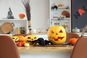 Halloween pumpkins with toy spider on dining table in kitchen