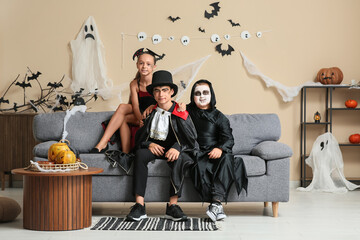 Kids dressed for Halloween sitting on sofa at home