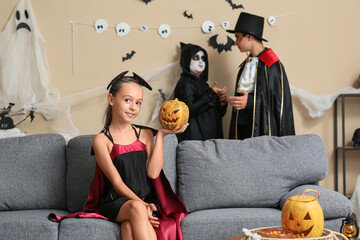 Teenage girl dressed for Halloween with pumpkin sitting on sofa at party