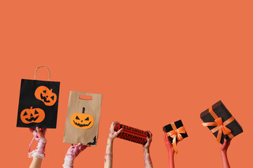 Mummy, zombie and devil hands with gift boxes and shopping bags on orange background. Halloween...