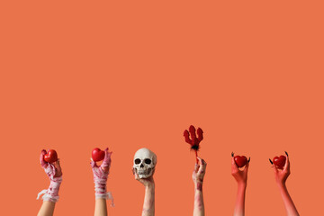 Mummy, zombie and devil hands with Halloween decorations on orange background