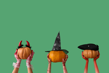 Mummy, zombie and devil hands holding pumpkins with Halloween headband on green background