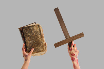 Zombie hands with old book and wooden cross on grey background. Halloween celebration