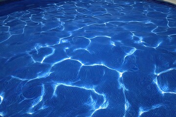Fototapeta premium Sun-dappled blue pool water, rippled texture