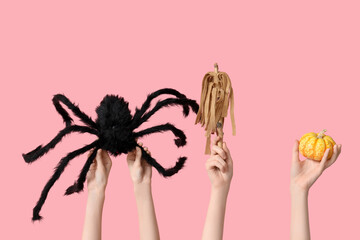 Female hands with spider, stick and pumpkin on pink background. Halloween celebration