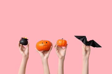 Female hands with pot, pumpkins and paper bat on pink background. Halloween celebration