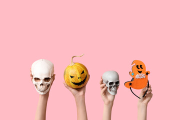 Female hands with skulls, pumpkin and funny ghost on pink background. Halloween celebration