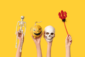 Female hands with pitchfork,  skeleton, pumpkin and skull on yellow background. Halloween...