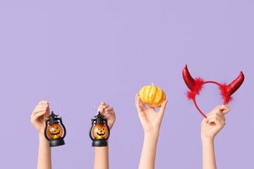 Female hands with lanterns, pumpkin and red devil horns headband with horns on lilac background....