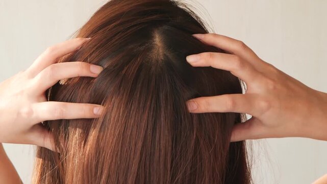 若いアジア人女性は頭皮をマッサージしています。
