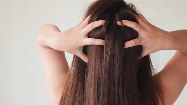 若いアジア人女性は頭皮をマッサージしています。