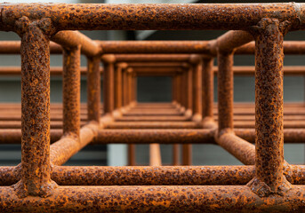 A close up perspective of a rusty metal structure with a square grid pattern receding away