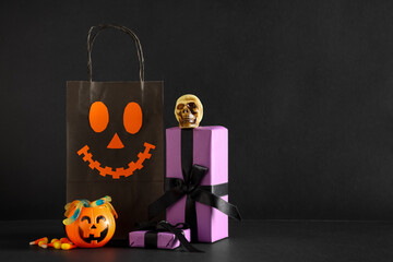 Shopping bag with gift boxes, candies and Halloween decorations on black background
