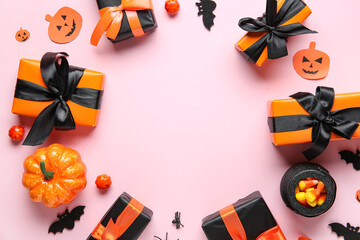 Frame made of Halloween gifts, pumpkins, bats and pot with candies on pink background. Top view