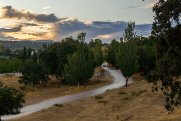 Scenic view of a white car driving on a winding road through a tranquil countryside landscape at sunset