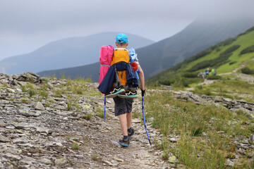 Boy with Backpack and Trekking Poles Hiking on a Mountain Trail