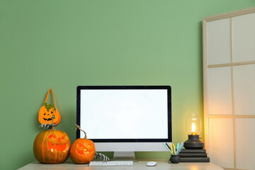 Workplace with computer and pumpkins in office interior decorated for Halloween celebration