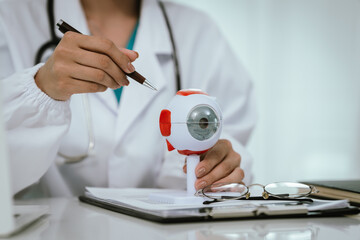 An Asian ophthalmologist examines an elderly patient's eyes for conditions like cataracts,...