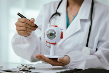 An Asian ophthalmologist examines an elderly patient's eyes for conditions like cataracts,...