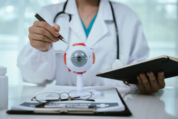 An Asian ophthalmologist examines an elderly patient's eyes for conditions like cataracts,...