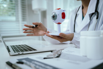 An Asian ophthalmologist examines an elderly patient's eyes for conditions like cataracts,...