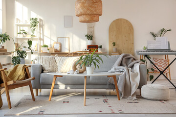 Interior of light living room with sofa, plants and synthesizer