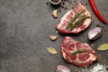 Fresh raw steaks and different spices on dark background