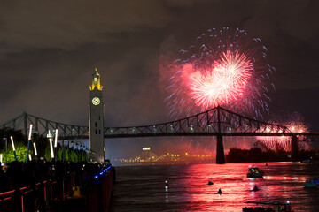 Montreal Clock Tower and Jacques Cartier Bridge with fireworks at night during summer celebration....