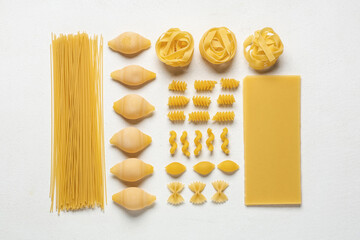 Composition with different types of raw pasta on white background