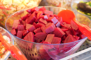 Colorful beetroot cubes in a clear bowl at a market stand