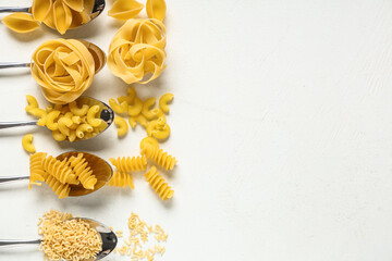 Spoons with different types of raw pasta on white background, closeup