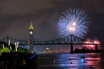 Montreal Clock Tower and Jacques Cartier Bridge with fireworks at night during summer celebration....