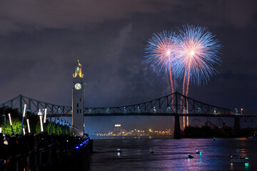 Montreal Clock Tower and Jacques Cartier Bridge with fireworks at night during summer celebration....