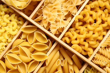 Box with different types of raw pasta as background, closeup