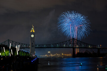 Montreal Clock Tower and Jacques Cartier Bridge with fireworks at night during summer celebration....
