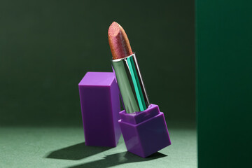 Composition with beautiful lipstick on green background, closeup