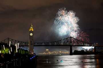 Montreal Clock Tower and Jacques Cartier Bridge with fireworks at night during summer celebration....