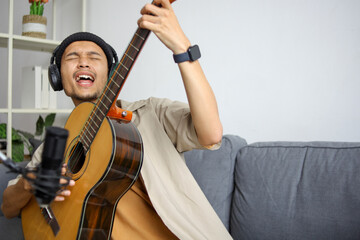 Enthusiastic Musician With Beanie And Headphones Singing Passionately While Holding His Guitar