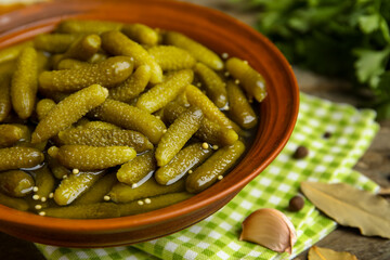Bowl with tasty pickled cucumbers and different spices on wooden background, closeup