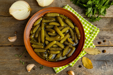 Bowl with tasty pickled cucumbers and different spices on wooden background