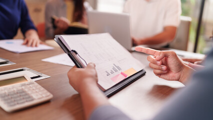 Business professionals collaborating analyzing financial data pointing report documents in modern office meeting room for strategic planning corporate growth