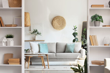 Interior of living room with comfortable sofa, tables and shelving units