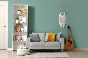 Shelving unit, guitar and sofa near green wall in interior of modern room