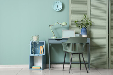 Interior of living room with table, folding screen and shelving unit near mint wall