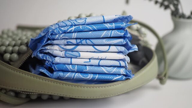 a stack of individually wrapped sanitary pads in a handbag