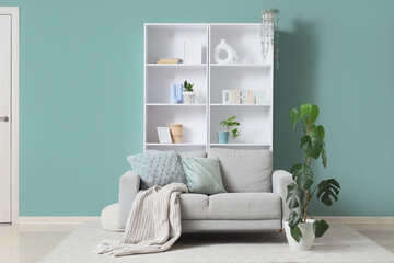 Interior of living room with comfortable sofa and shelving unit near mint wall