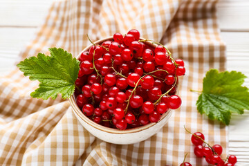 Bowl with fresh red currants on white wooden background, closeup